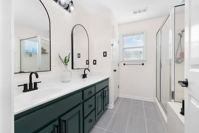 a spacious bathroom with a double vanity sink a mirror a shower and a mirror