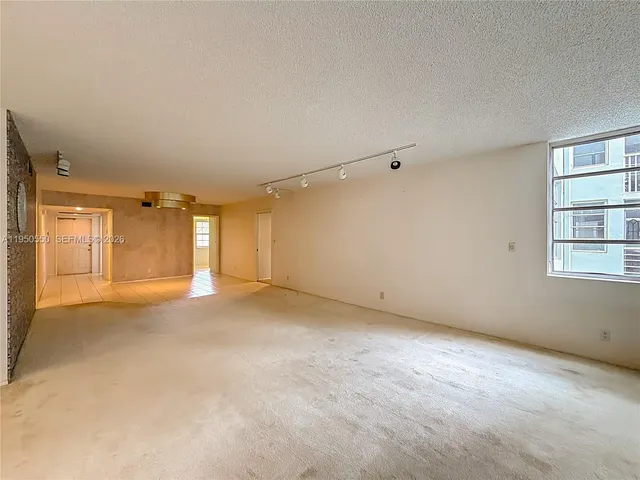 an empty room with windows and ceiling fan