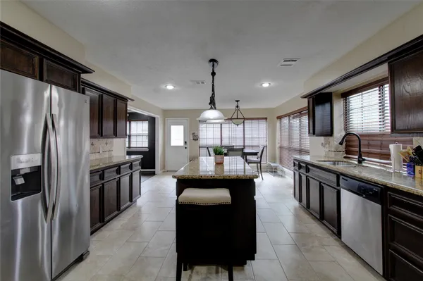 a large kitchen with kitchen island a large counter top space a sink stainless steel appliances and cabinets
