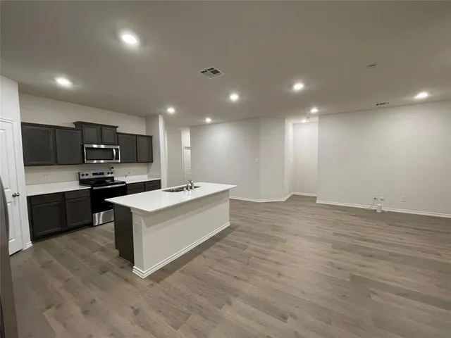 a view of kitchen with stainless steel appliances refrigerator oven and white cabinets with wooden floor