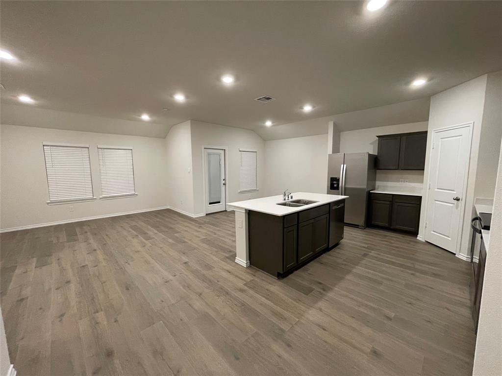 1452 Millstead Rill Road Caddo Mills, TX 75135 - Photo 24 of 24 Kitchen featuring vaulted ceiling, appliances with stainless steel finishes, a kitchen island with sink, open floor plan, and light wood-style flooring