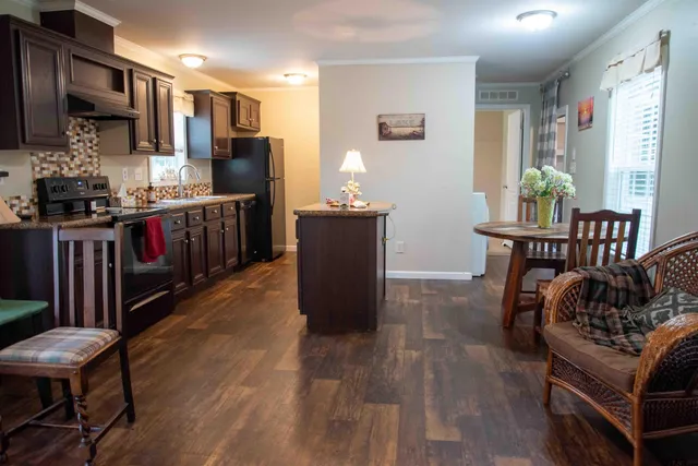 a kitchen with stainless steel appliances kitchen island granite countertop a table chairs and a refrigerator