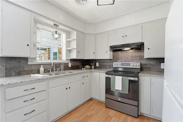 a kitchen with granite countertop a refrigerator stove and sink