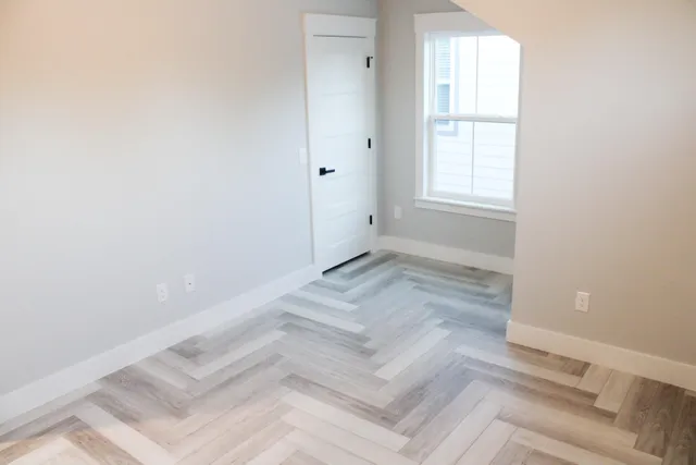 an empty room with a white bed and a window