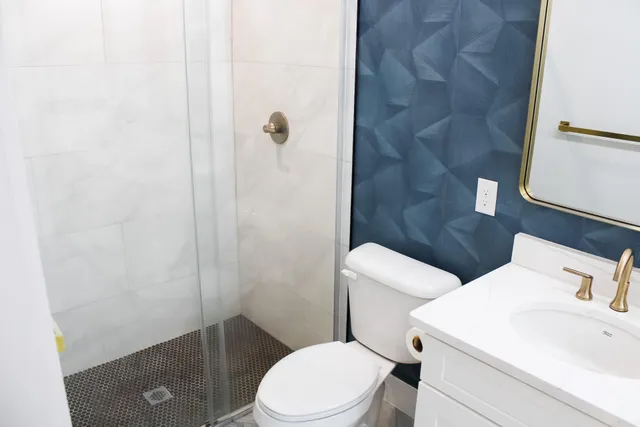 a white toilet sitting next to a bathroom sink and a shower