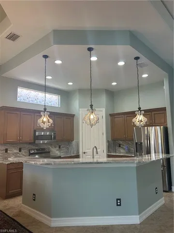 a view of a kitchen with granite countertop stainless steel appliances and a chandelier