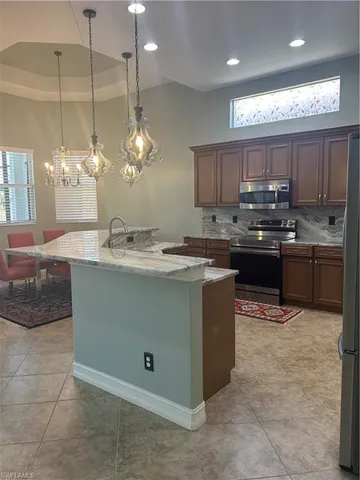 a kitchen with kitchen island granite countertop a sink counter top space appliances and cabinets