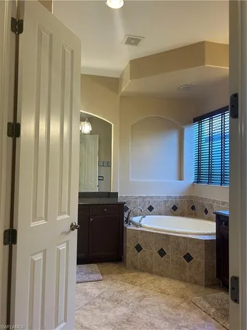 a spacious bathroom with a tub a double vanity sink and mirror