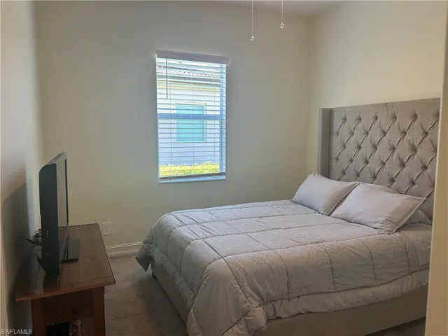 a bedroom with a bed flat screen tv and window