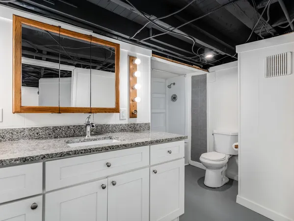 a bathroom with a granite countertop sink mirror and toilet