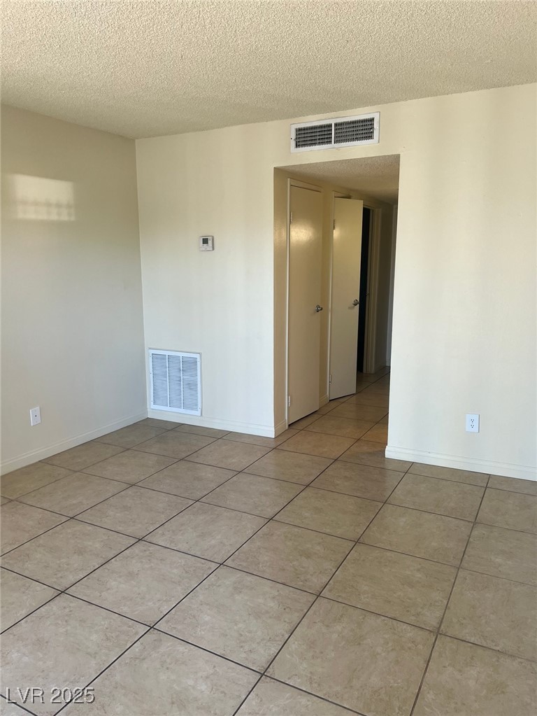 1388 East Desert Inn Road, Unit 1 Las Vegas, NV 89169 - Photo 5 of 17 Spare room featuring a textured ceiling, light tile patterned floors, and baseboards