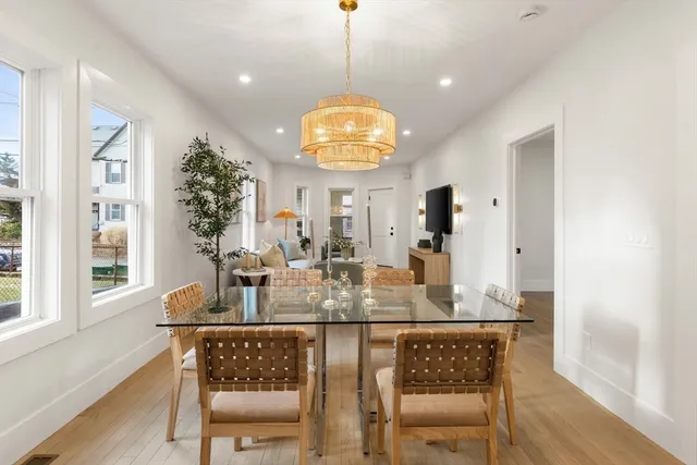 a dining room with wooden floor a chandelier a wooden table and chairs