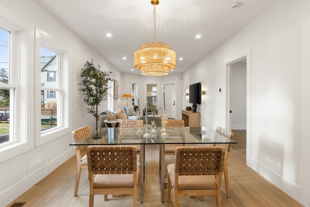 7 Bennett Street, Unit 1 Medford, MA 02155 - Photo 5 of 38 a dining room with wooden floor a chandelier a wooden table and chairs