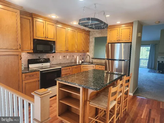 a kitchen with stainless steel appliances granite countertop a sink dishwasher stove and refrigerator with wooden floor