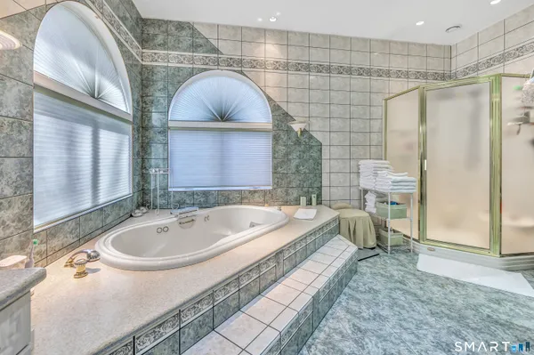 a bathroom with a tub a sink and a large mirror