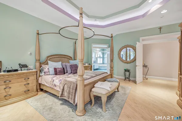 a bedroom with a bed a mirror on dresser and a chandelier