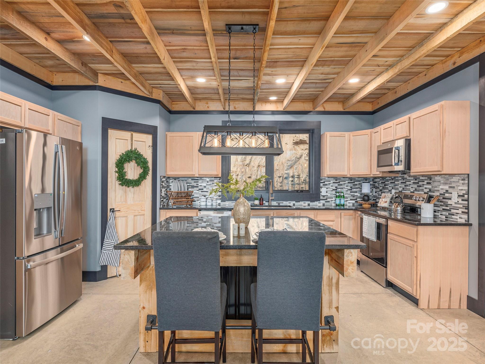 55 Dean Riddle Drive Waynesville, NC 28785 - Photo 11 of 35 a kitchen with stainless steel appliances granite countertop a stove a refrigerator a kitchen island a table and chairs