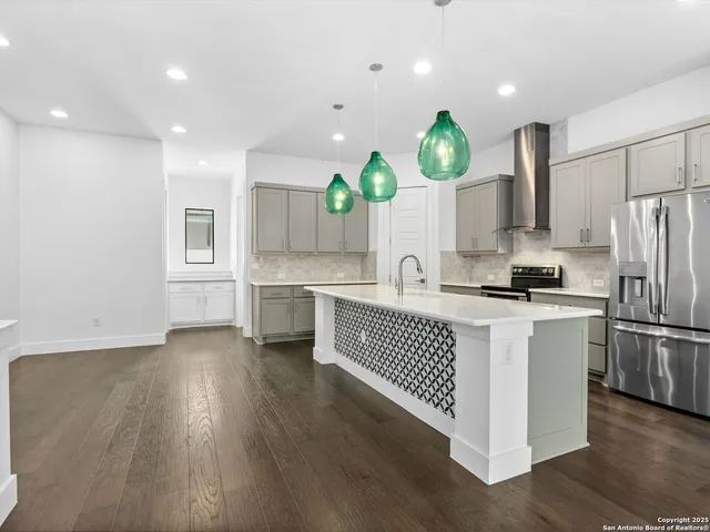 a kitchen with stainless steel appliances granite countertop a sink a stove a refrigerator cabinets and wooden floor