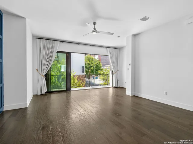 an empty room with wooden floor fan and windows