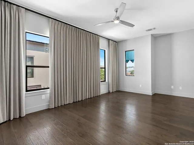 an empty room with wooden floor staircase and windows
