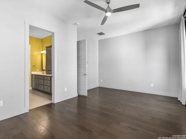 an empty room with wooden floor cabinet and windows
