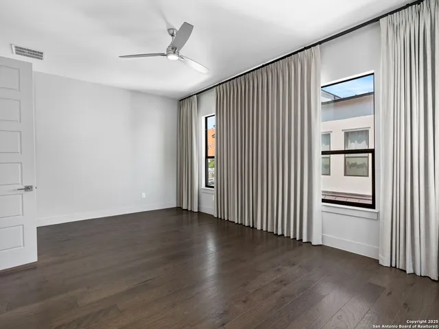 an empty room with wooden floor cabinet and windows