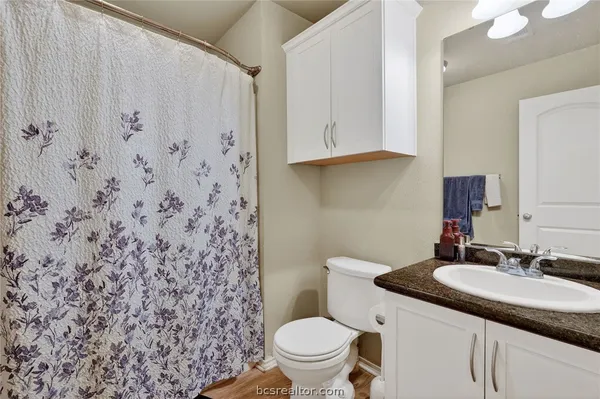 a bathroom with a granite countertop sink and a toilet