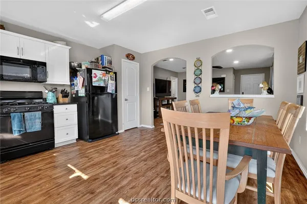 a living room with stainless steel appliances kitchen island granite countertop a dining table chairs and a refrigerator
