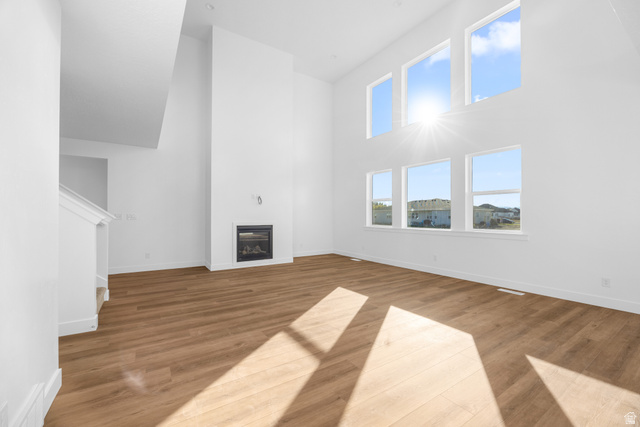 1510 West 600 North, Unit 4A Mapleton, UT 84664 - Photo 6 of 23 Unfurnished living room featuring a towering ceiling, light wood-style flooring, and a glass covered fireplace