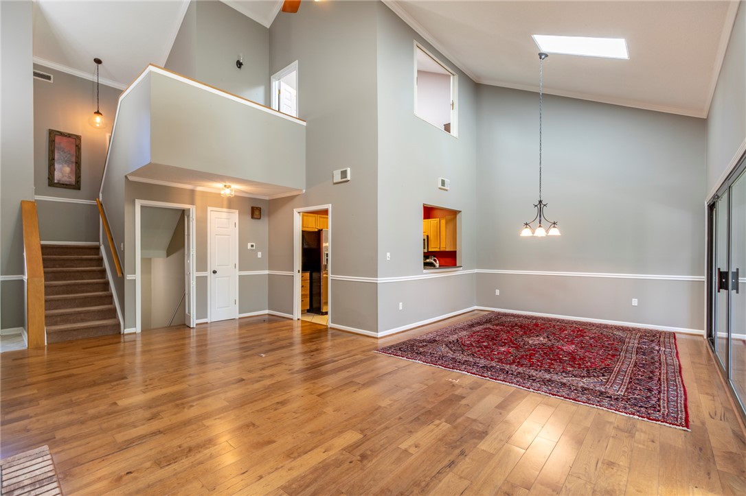 1302 Leeward Road Anderson, SC 29625 - Photo 7 of 50 A grand, naturally illuminated living room showcasing rich hardwood floors and an elegant chandelier.