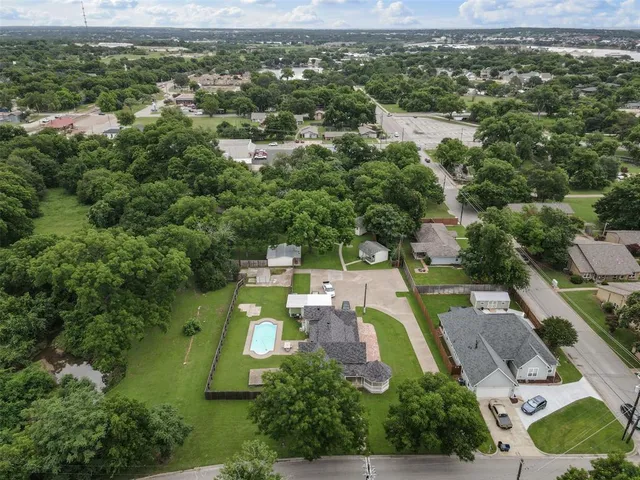 an aerial view of residential houses with outdoor space and trees