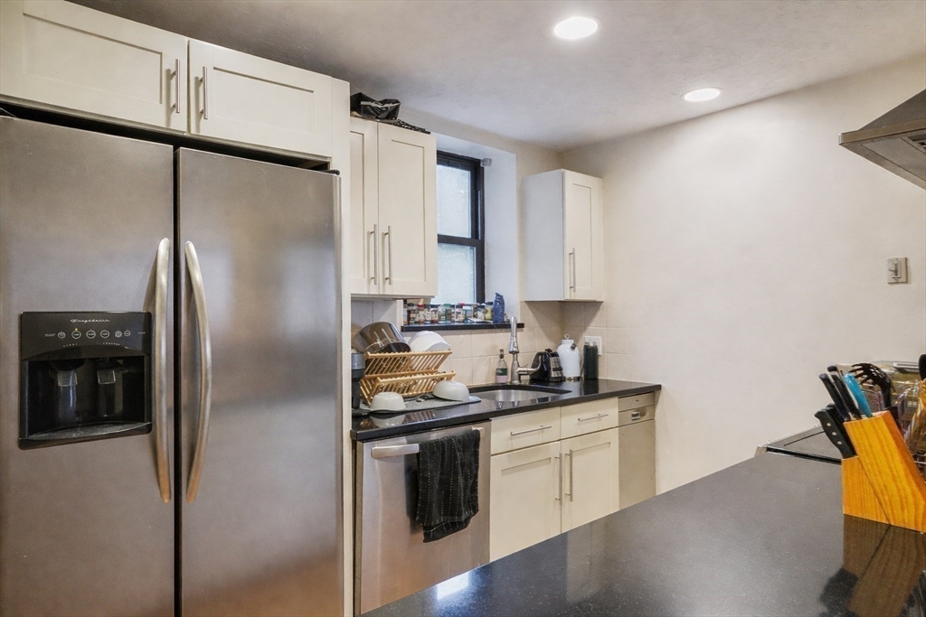 841 Parker Street, Unit 101 Boston, MA 02120 - Photo 5 of 19 a kitchen with stainless steel appliances a refrigerator sink and cabinets