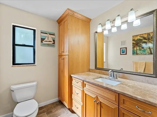 a bathroom with a granite countertop toilet sink and mirror