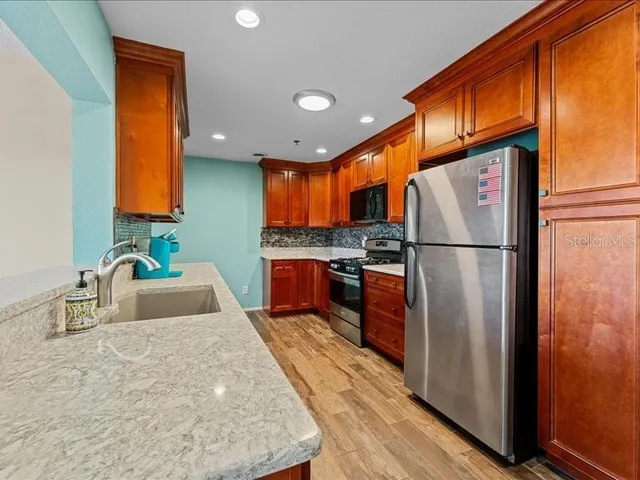 a kitchen with stainless steel appliances granite countertop a refrigerator a sink and a stove