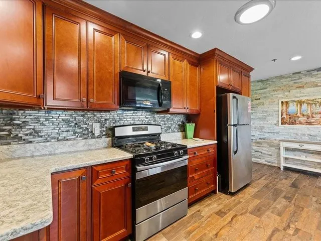 a kitchen with stainless steel appliances granite countertop a stove a refrigerator and a microwave