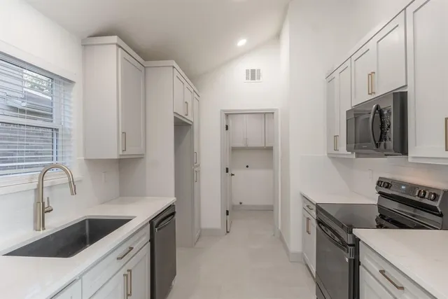 a kitchen with granite countertop white cabinets stainless steel appliances and a sink