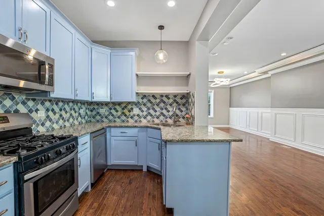 a kitchen with granite countertop stainless steel appliances a sink cabinets and wooden floor