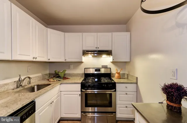 a kitchen with granite countertop a sink a stove and cabinets