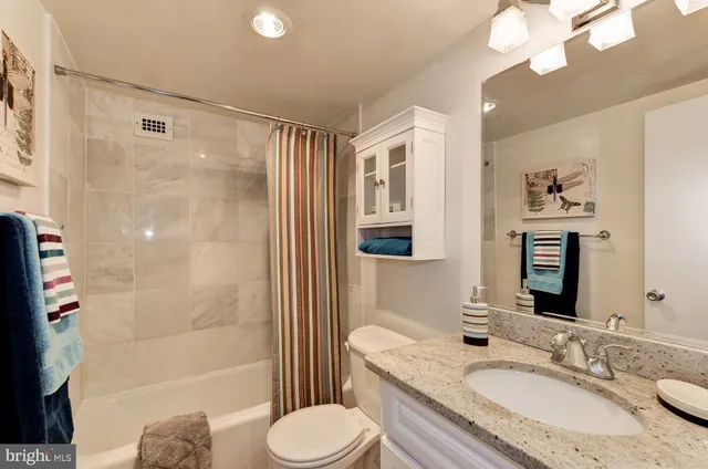 a bathroom with a granite countertop sink toilet a mirror a bathtub and shower