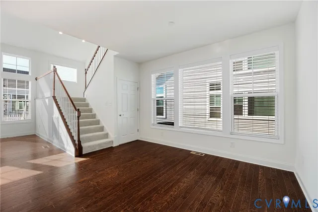 a view of an empty room with wooden floor and stairs