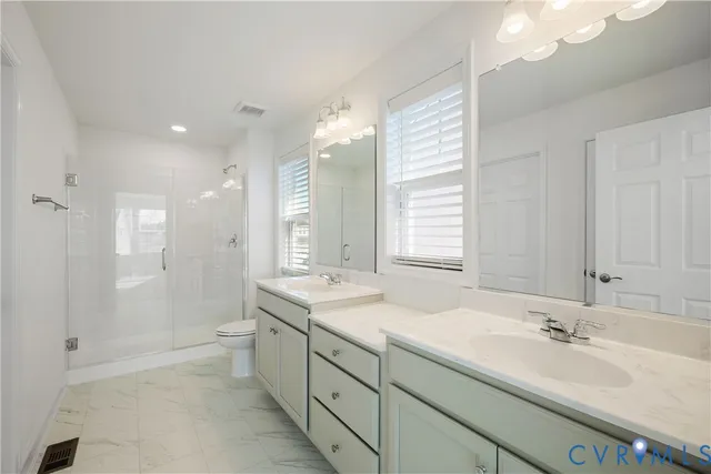 a bathroom with a sink double vanity granite tub shower and a mirror