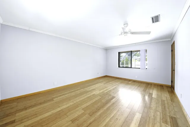 an empty room with wooden floor chandelier and windows