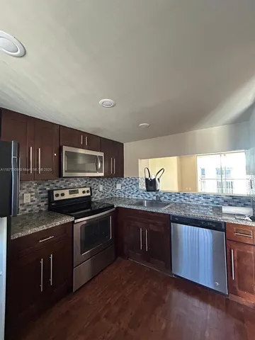 a kitchen with stainless steel appliances granite countertop a stove a sink and a microwave