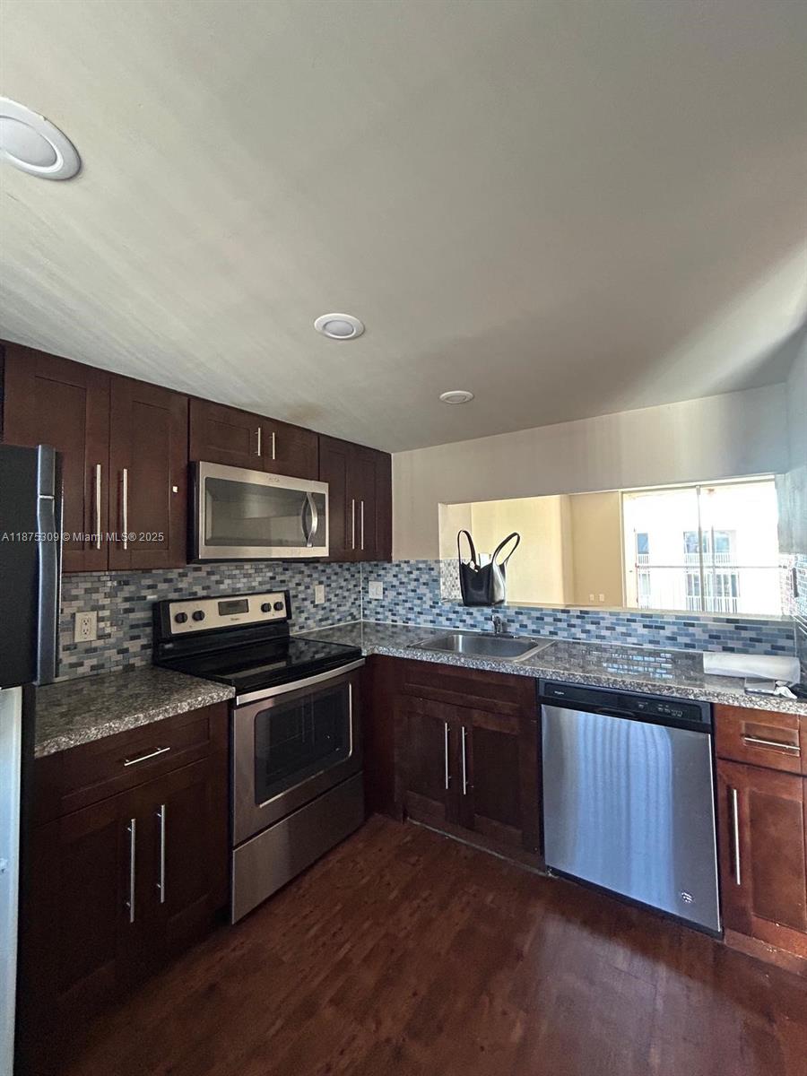 a kitchen with stainless steel appliances granite countertop a stove a sink and a microwave