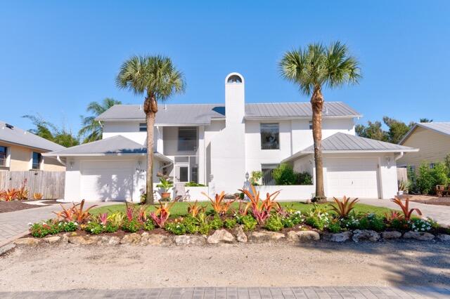 5125 Southeast Matousek Street Stuart, FL 34997 - Photo 3 of 39 a front view of a house with a yard and a garden