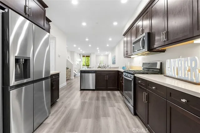 a kitchen with stainless steel appliances granite countertop refrigerator a sink a stove top oven and wooden floor