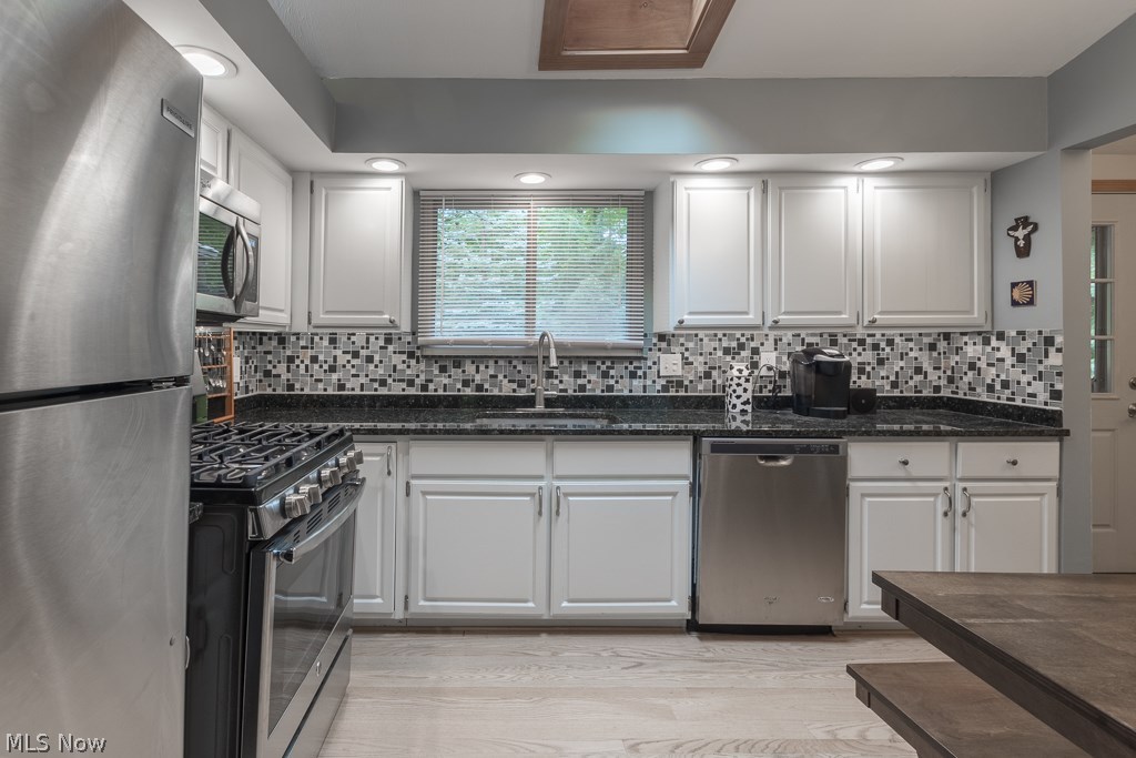 11799 Girdled Road Painesville, OH 44077 - Photo 6 of 26 White cabinets, granite countertops, new backsplash, LED lighting and wood laminate flooring make this kitchen a winner!