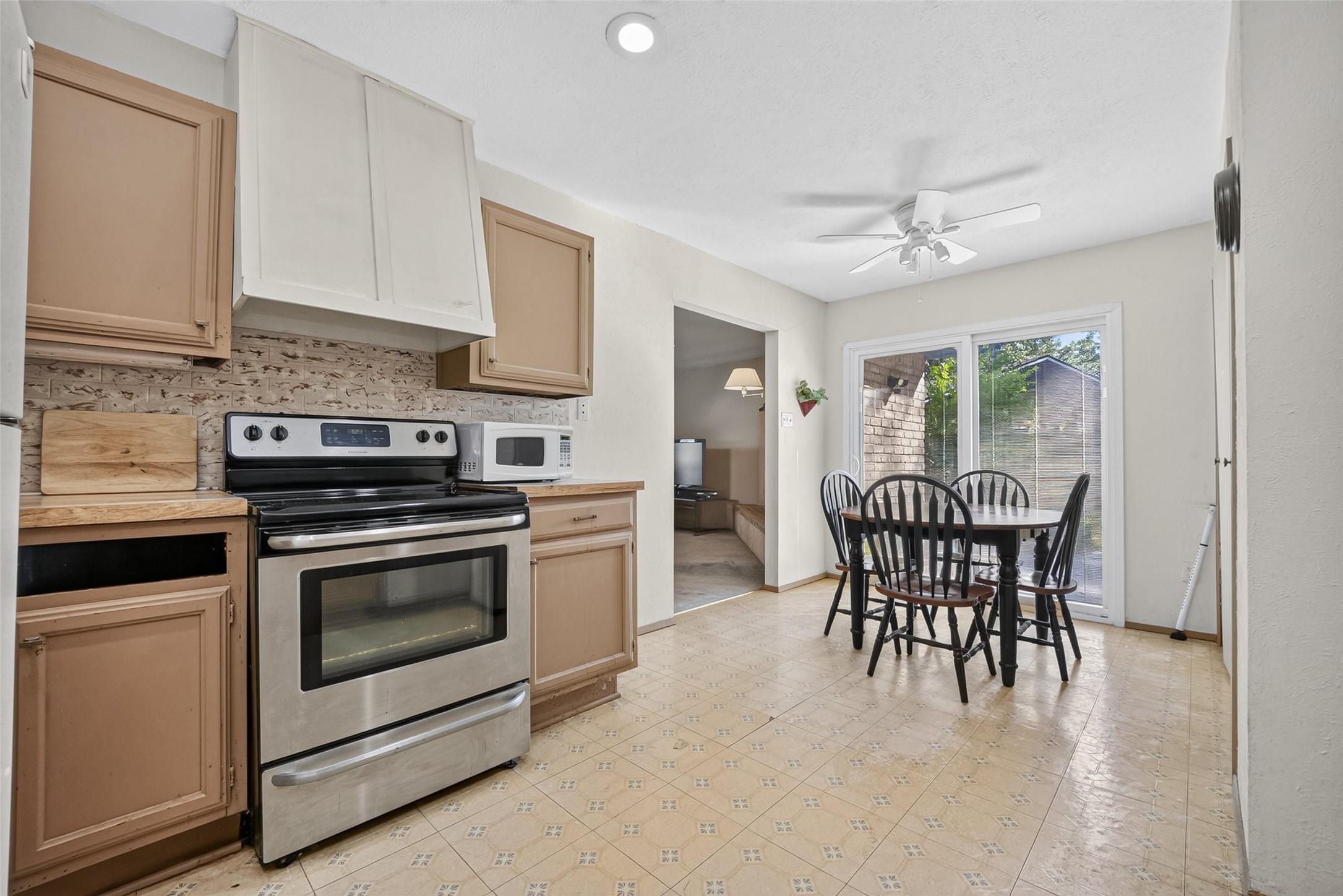 22926 Millgate Drive Spring, TX 77373 - Photo 14 of 34 This kitchen features a cozy dining area with sliding glass doors leading to the backyard, offering plenty of natural light. The space includes a modern stainless steel stove and a mix of upper and lower cabinets for ample storage.