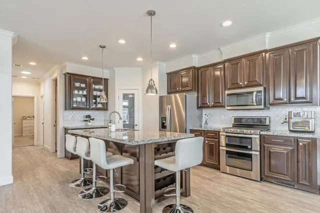 a kitchen with stainless steel appliances kitchen island granite countertop a refrigerator and a stove top oven