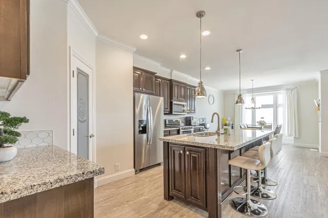 a kitchen with stainless steel appliances granite countertop a sink a refrigerator and a counter top space